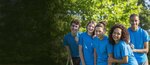 Mehrere Jugendliche alle in blauen T-Shirts die zusammen stehen.