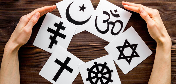 Hände umarmen das Christentum, den Katholizismus, den Buddhismus, den Judentum, Islam-Symbole auf Holzhintergrund