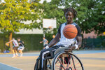 Mann mit Behinderung im Rollstuhl auf einem Basketballplatz