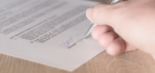Ausschnitt einer Hand, die einen Vertrag unterzeichnet